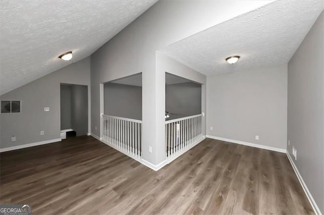 spare room with dark hardwood / wood-style flooring, a textured ceiling, and lofted ceiling