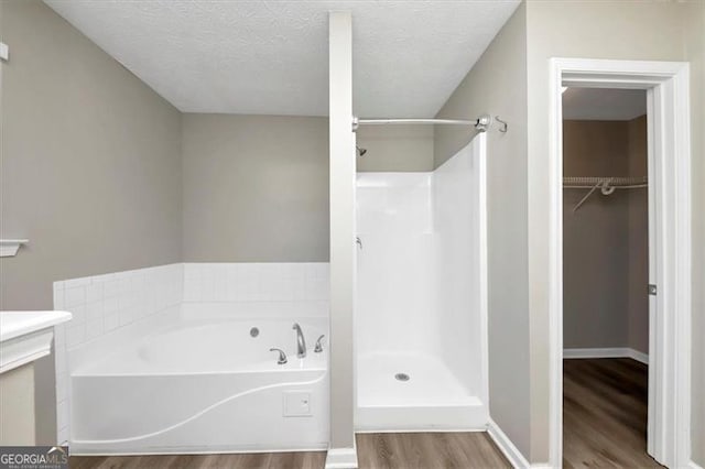 bathroom featuring plus walk in shower, wood-type flooring, and a textured ceiling