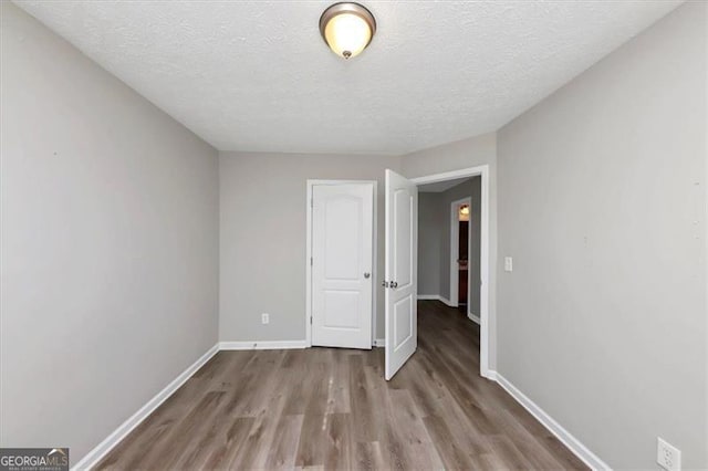 spare room featuring light hardwood / wood-style flooring and a textured ceiling