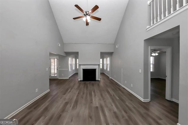 unfurnished living room with dark hardwood / wood-style flooring, high vaulted ceiling, and ceiling fan