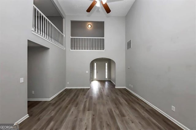 entryway featuring ceiling fan, a towering ceiling, and dark wood-type flooring