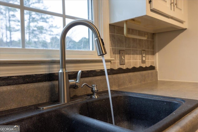 details with white cabinetry, sink, and decorative backsplash