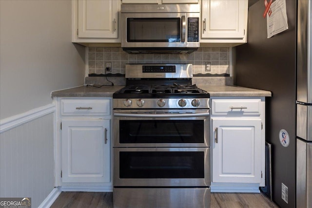 kitchen featuring stainless steel appliances, hardwood / wood-style floors, white cabinets, and decorative backsplash