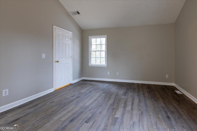 unfurnished room with vaulted ceiling, dark wood-type flooring, and a textured ceiling