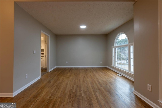 spare room with hardwood / wood-style floors and a textured ceiling