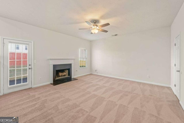 unfurnished living room featuring a textured ceiling, ceiling fan, light carpet, and a wealth of natural light