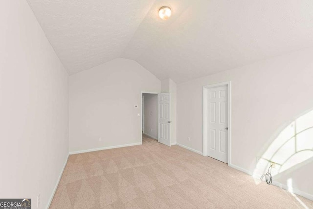 bonus room featuring a textured ceiling, light colored carpet, and lofted ceiling