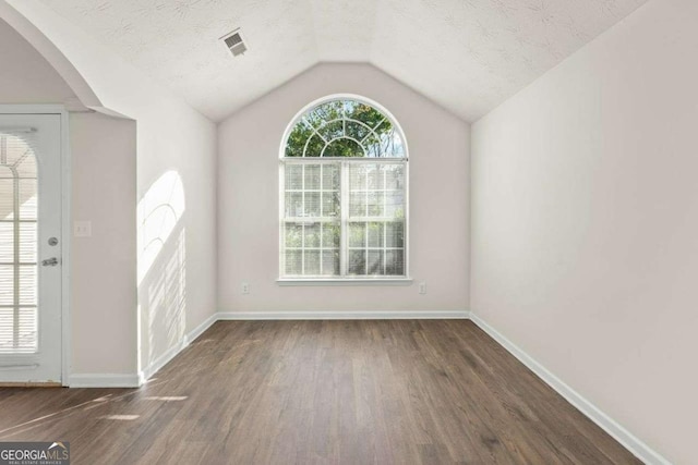 foyer featuring dark wood-type flooring, a textured ceiling, and vaulted ceiling