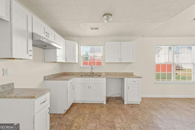 kitchen with sink, white cabinets, and a textured ceiling