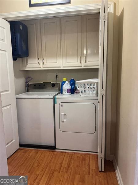 laundry room with washer and dryer, cabinets, and light hardwood / wood-style flooring