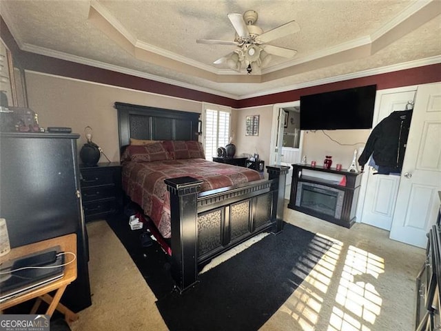 carpeted bedroom featuring ceiling fan, a raised ceiling, a textured ceiling, and crown molding