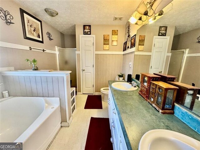 full bathroom with vanity, shower with separate bathtub, a textured ceiling, and toilet