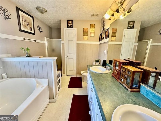 full bathroom with vanity, toilet, a textured ceiling, and independent shower and bath