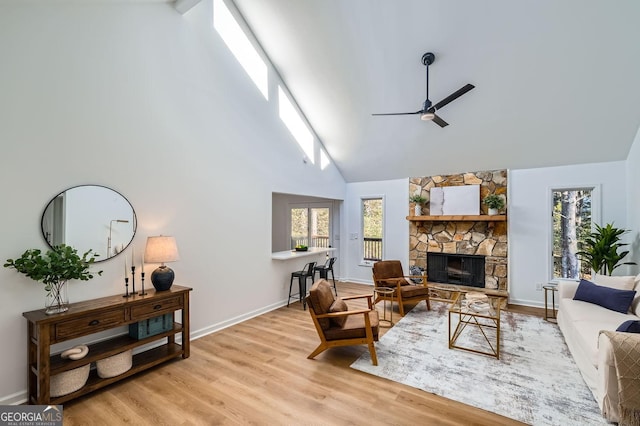 living room with a fireplace, a wealth of natural light, light hardwood / wood-style floors, and ceiling fan