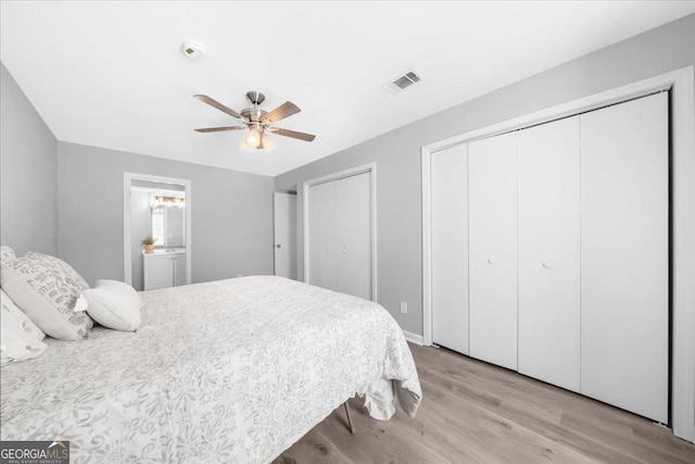 bedroom featuring ceiling fan, light wood-type flooring, connected bathroom, and two closets