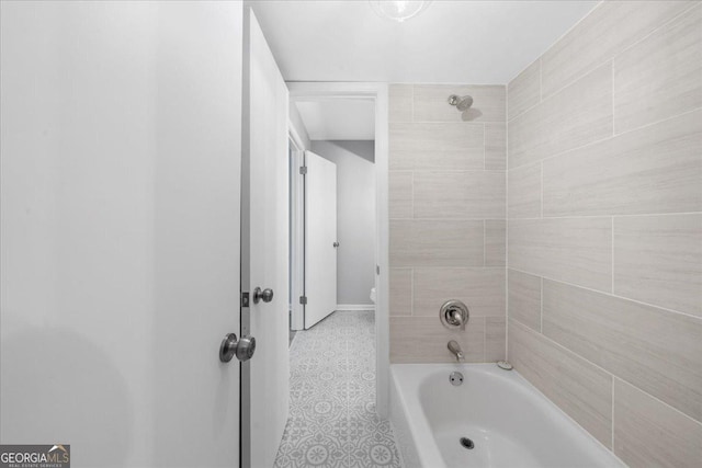 bathroom featuring tiled shower / bath combo and toilet