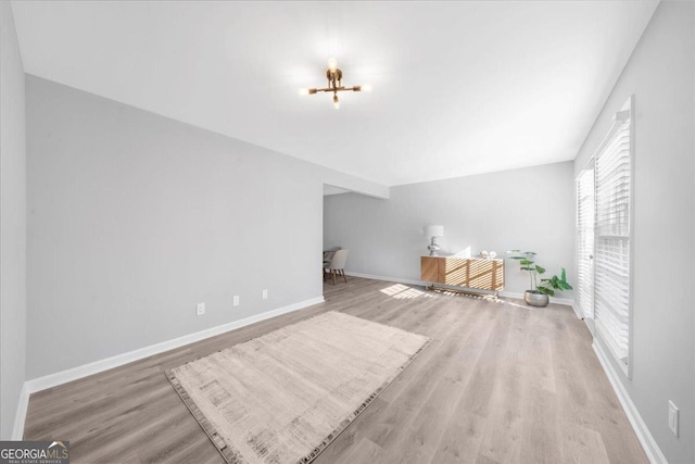 unfurnished living room featuring a notable chandelier and light hardwood / wood-style floors