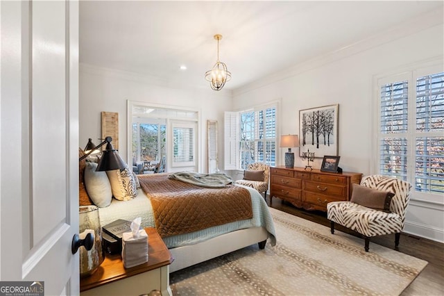 bedroom featuring wood-type flooring, an inviting chandelier, and ornamental molding