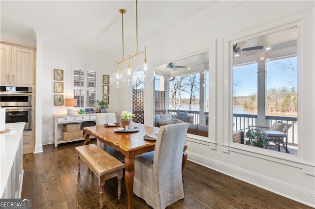 dining room featuring a water view, dark hardwood / wood-style floors, ornamental molding, and ceiling fan