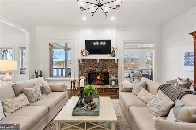 living room featuring hardwood / wood-style flooring, a fireplace, ornamental molding, and an inviting chandelier