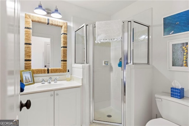 bathroom featuring vanity, a shower with shower door, and toilet