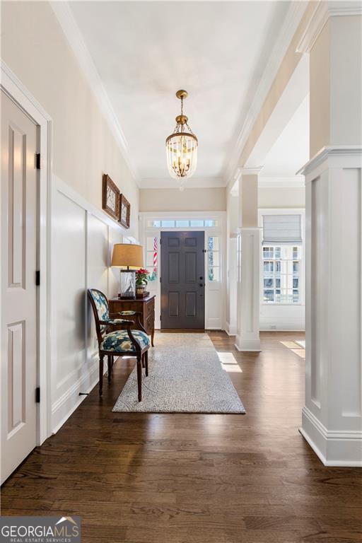 entryway with a chandelier, dark hardwood / wood-style floors, ornate columns, and crown molding