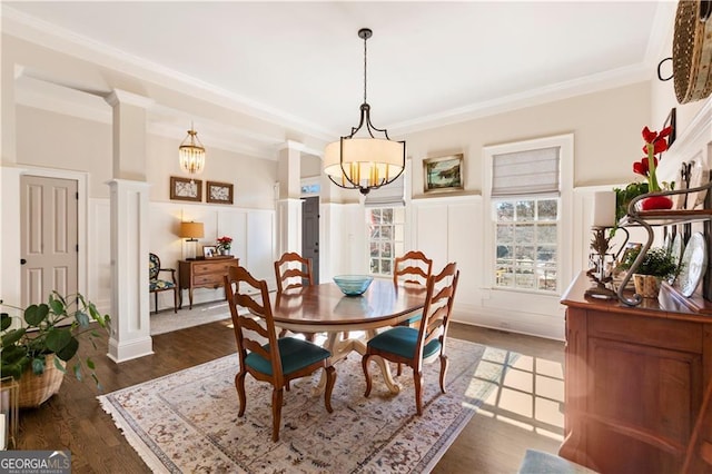 dining area with decorative columns, crown molding, dark wood-type flooring, and a notable chandelier