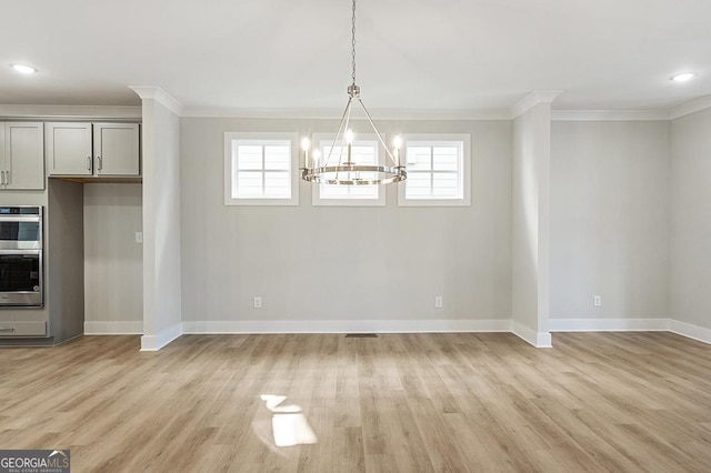 unfurnished dining area featuring a wealth of natural light, light hardwood / wood-style flooring, an inviting chandelier, and ornamental molding