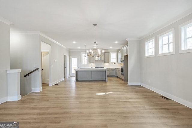 kitchen featuring a center island, gray cabinets, a wealth of natural light, and crown molding