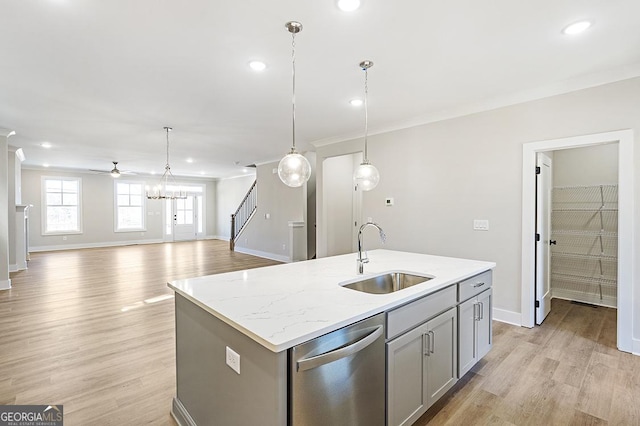 kitchen featuring ceiling fan, dishwasher, sink, an island with sink, and decorative light fixtures