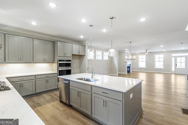 kitchen featuring ceiling fan, gray cabinets, light stone counters, and sink