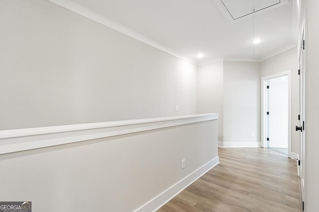 corridor with light hardwood / wood-style floors and ornamental molding