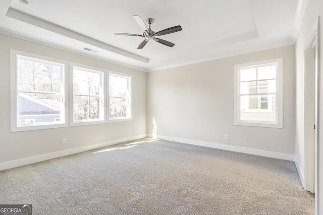 unfurnished room with a tray ceiling, ceiling fan, and plenty of natural light