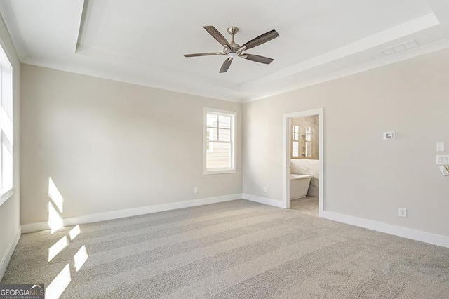 unfurnished room featuring ceiling fan, light colored carpet, and a tray ceiling