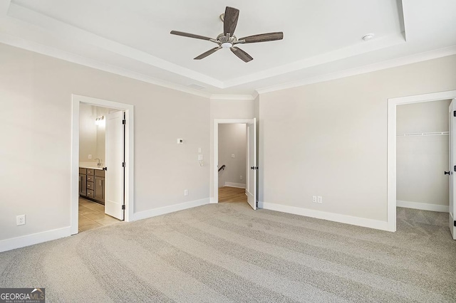 unfurnished bedroom with ensuite bathroom, ceiling fan, a spacious closet, light colored carpet, and a closet