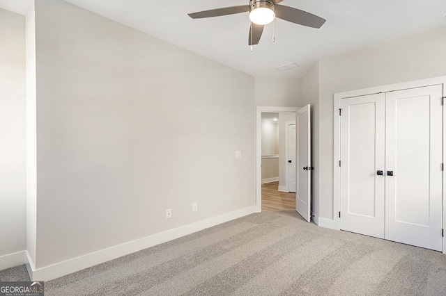 unfurnished bedroom with ceiling fan, light carpet, and a closet