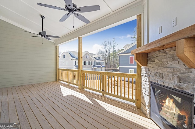 wooden terrace featuring an outdoor stone fireplace and ceiling fan