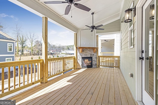 wooden deck with an outdoor stone fireplace