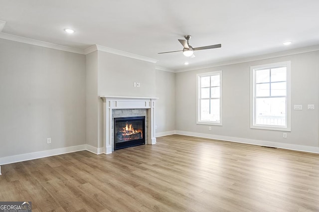 unfurnished living room featuring ceiling fan, light hardwood / wood-style floors, ornamental molding, and a high end fireplace