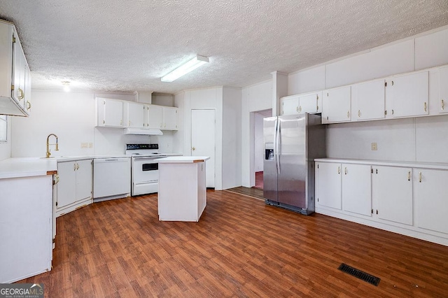 kitchen with white appliances, white cabinets, a textured ceiling, and a center island