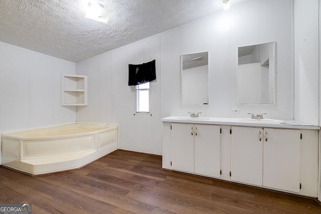 bathroom featuring a textured ceiling, a bathtub, wood-type flooring, and vanity