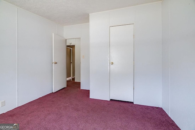 unfurnished bedroom featuring a closet, a textured ceiling, and light colored carpet