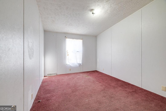 spare room with a textured ceiling and carpet flooring