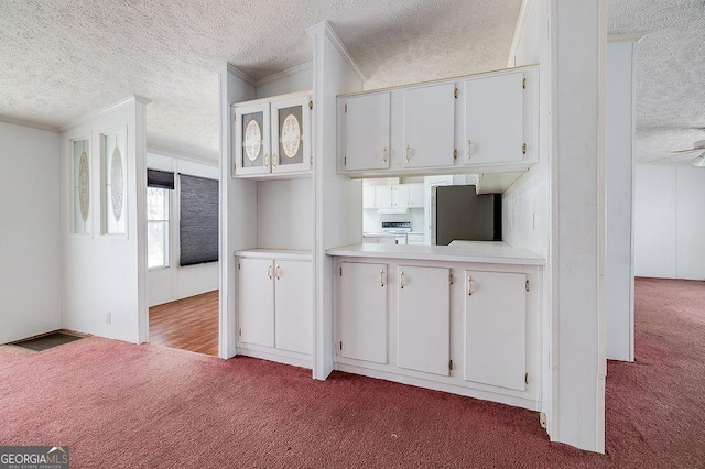 kitchen featuring light carpet, stainless steel refrigerator, crown molding, a textured ceiling, and white cabinets