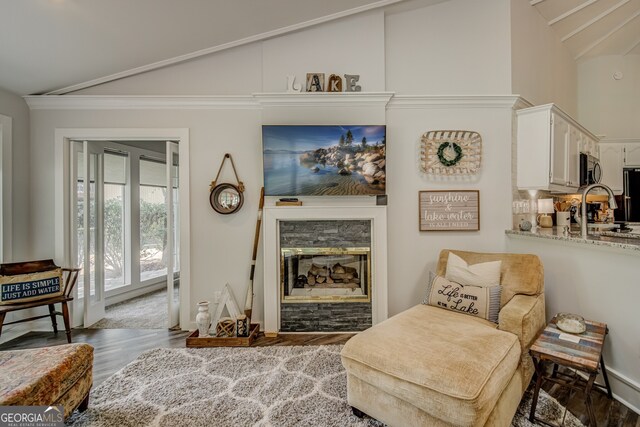 living area with a stone fireplace, dark wood-type flooring, and vaulted ceiling