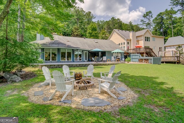 back of property with a lawn, an outdoor fire pit, and a wooden deck