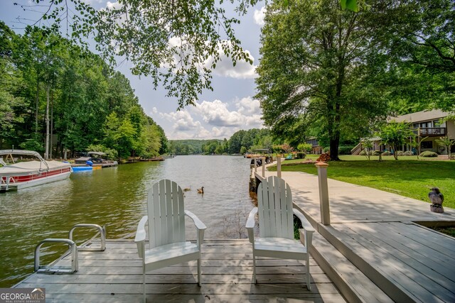 view of dock with a lawn and a water view