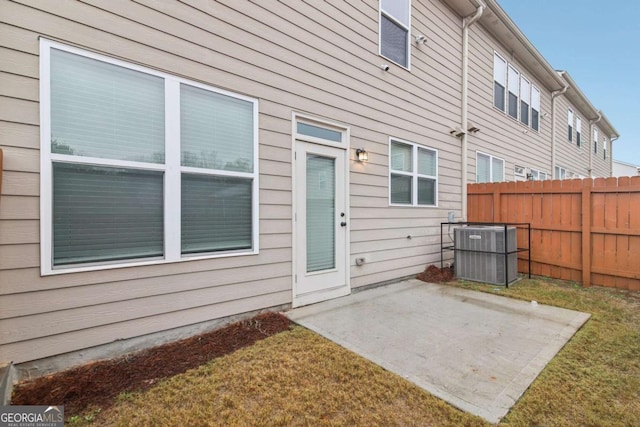 doorway to property with a patio, a lawn, and central air condition unit