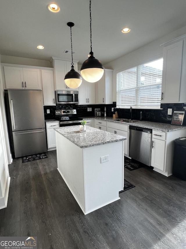 kitchen with white cabinetry, hanging light fixtures, and stainless steel appliances