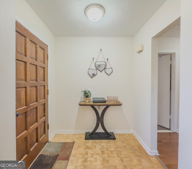 foyer entrance featuring a textured ceiling and light parquet floors